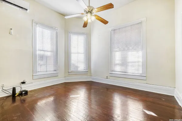 a view of empty room with wooden floor and fan