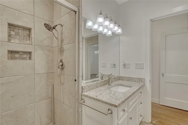 a bathroom with a granite countertop shower a sink and a mirror