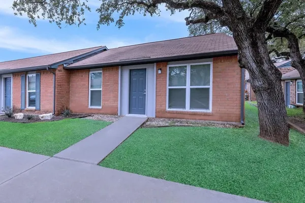 a brick house with a large tree