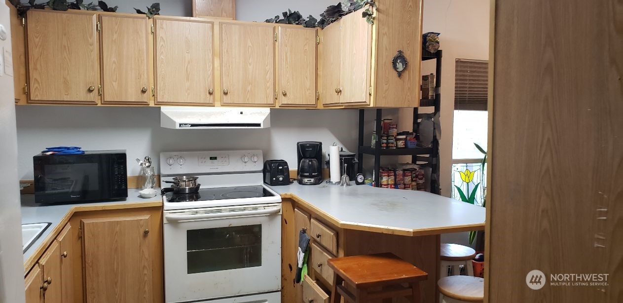 520 Willow Drive, Unit 111 Enumclaw, WA 98022 - Photo 3 of 26 a kitchen with a stove a refrigerator and a dining table