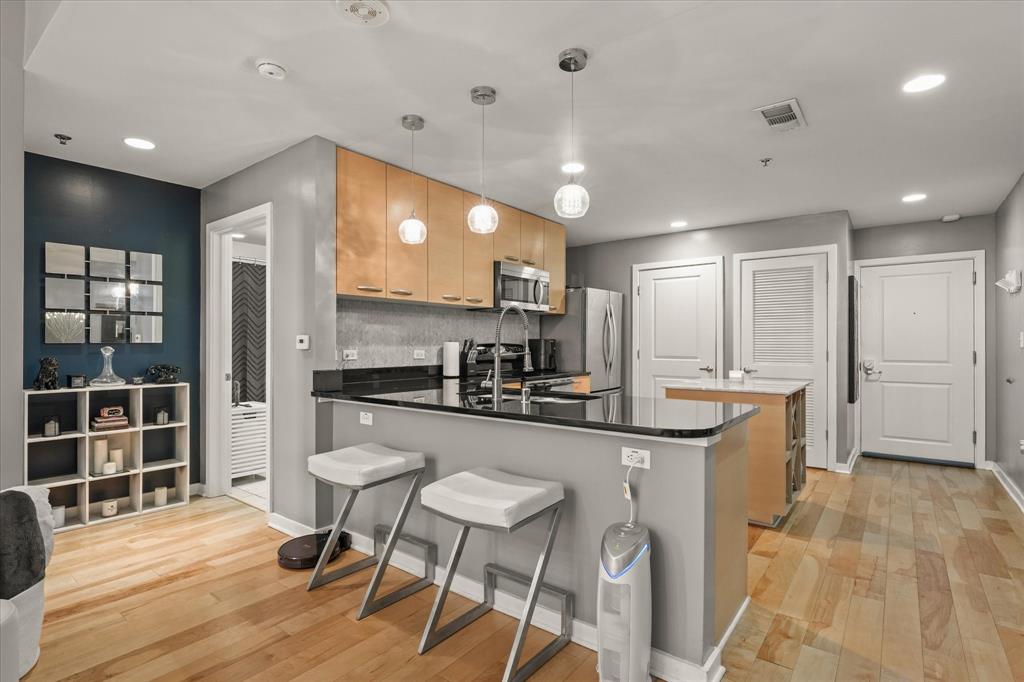1200 Main Street, Unit 1508 Dallas, TX 75202 - Photo 13 of 16 a kitchen with stainless steel appliances kitchen island granite countertop a refrigerator and wooden cabinets