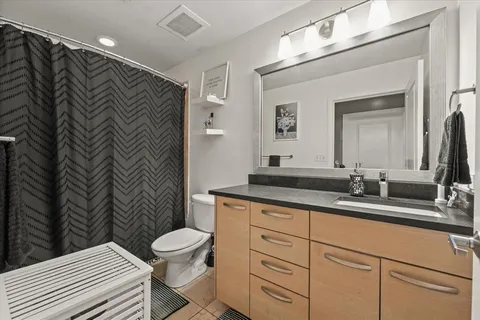 a bathroom with a granite countertop sink a toilet and a mirror