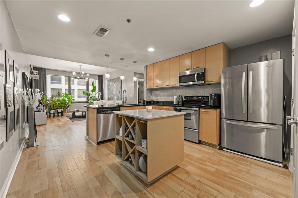 1200 Main Street, Unit 1508 Dallas, TX 75202 - Photo 10 of 16 a kitchen with kitchen island a counter top space a sink stainless steel appliances and cabinets