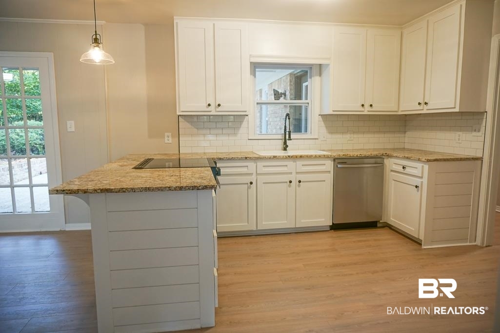 6205 Zeigler Boulevard Mobile, AL 36608 - Photo 11 of 17 Kitchen with a peninsula, dishwasher, tasteful backsplash, white cabinets, and light stone counters