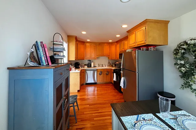 a kitchen with stainless steel appliances granite countertop a refrigerator a stove and a wooden floors