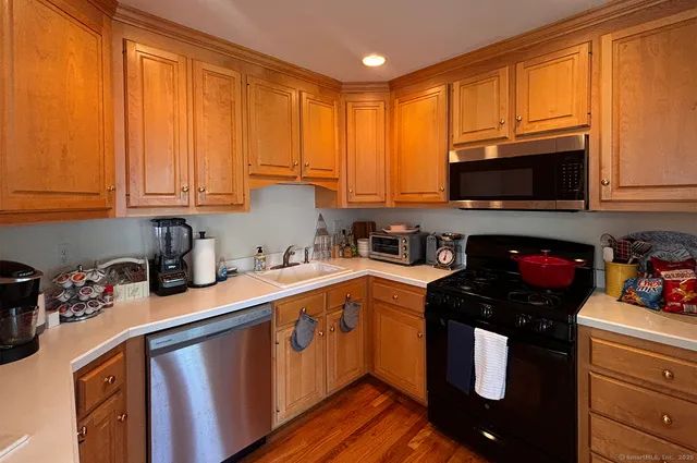 a kitchen with stainless steel appliances granite countertop a stove a sink dishwasher and a microwave with wooden cabinets