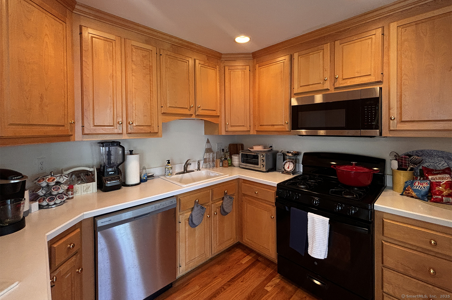 391 South Pine Creek Road Fairfield, CT 06824 - Photo 9 of 25 a kitchen with stainless steel appliances granite countertop a stove a sink dishwasher and a microwave with wooden cabinets
