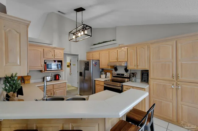 a kitchen with stainless steel appliances granite countertop a refrigerator a sink dishwasher a stove a dining table and chairs with wooden floor