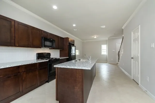 a kitchen with stainless steel appliances kitchen island granite countertop a stove sink and cabinets