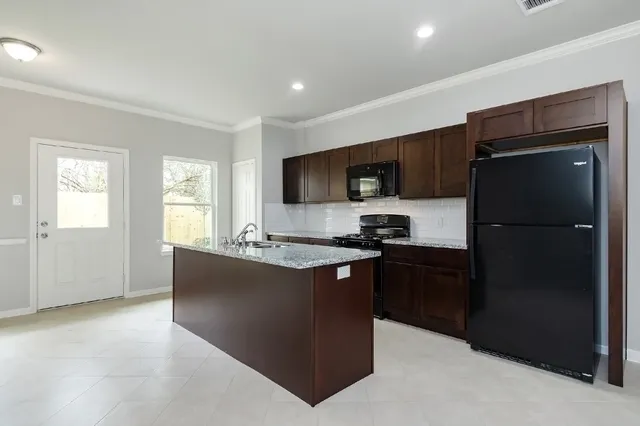 a kitchen with stainless steel appliances a sink a stove a refrigerator cabinets and a window