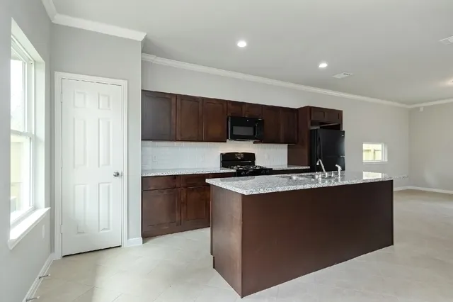 a kitchen with stainless steel appliances granite countertop a stove top oven a sink and a refrigerator