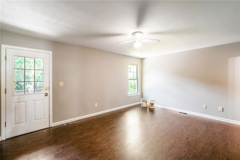 2045 Baker Road Northwest, Unit A Atlanta, GA 30318 - Photo 12 of 15 an empty room with wooden floor chandelier fan and windows