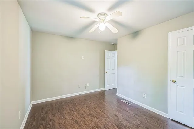an empty room with wooden floor and fan