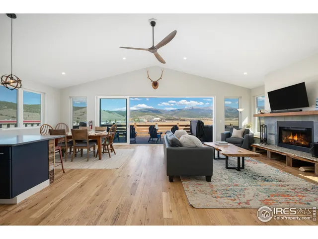 a living room with furniture dining table a fireplace and a large window