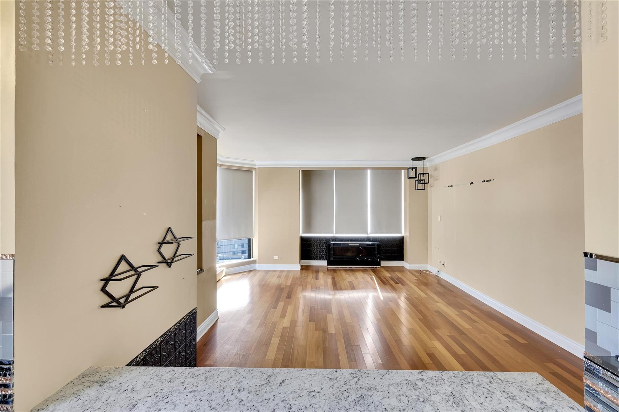 380 Rector Place, Unit 15E Manhattan, NY 10280 - Photo 14 of 31 Unfurnished living room with crown molding, wood finished floors, and baseboards