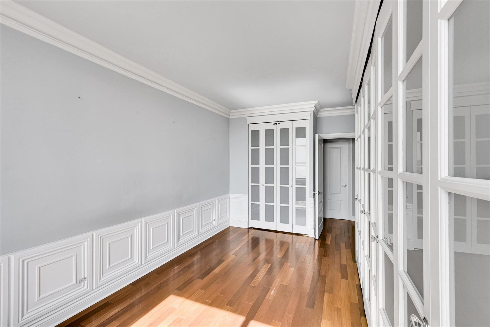 380 Rector Place, Unit 15E Manhattan, NY 10280 - Photo 26 of 31 Spare room featuring french doors, a wainscoted wall, wood finished floors, and ornamental molding