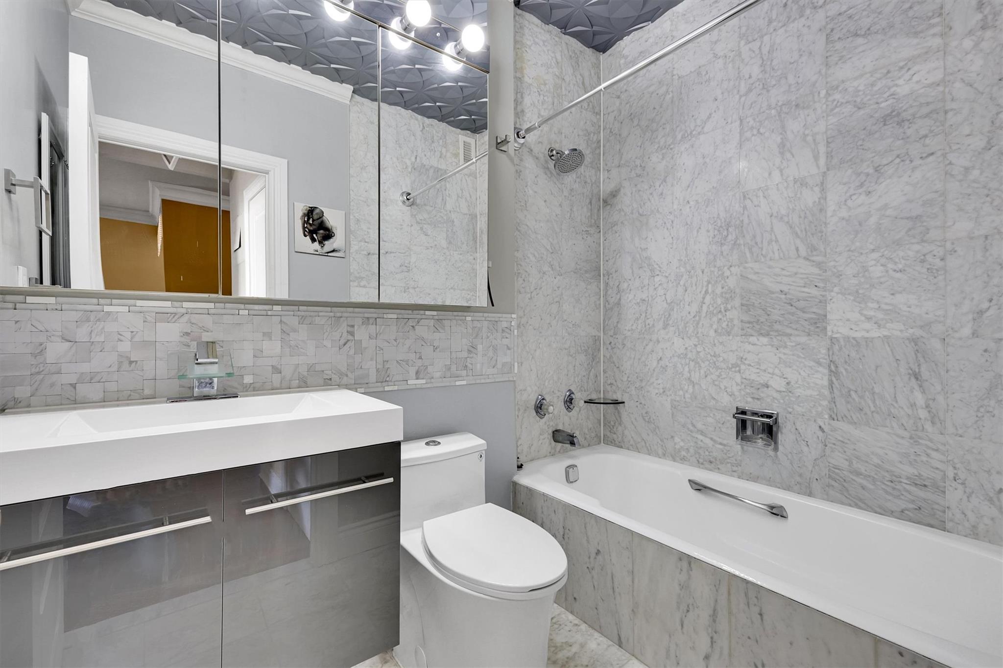 380 Rector Place, Unit 15E Manhattan, NY 10280 - Photo 29 of 31 Bathroom featuring backsplash, tile walls, toilet, shower / bath combination, and vanity