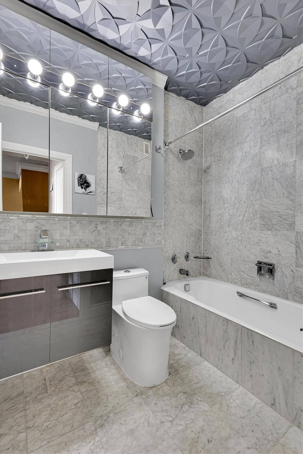 380 Rector Place, Unit 15E Manhattan, NY 10280 - Photo 30 of 31 Full bathroom featuring vanity, crown molding, tile walls, toilet, and tiled shower / bath