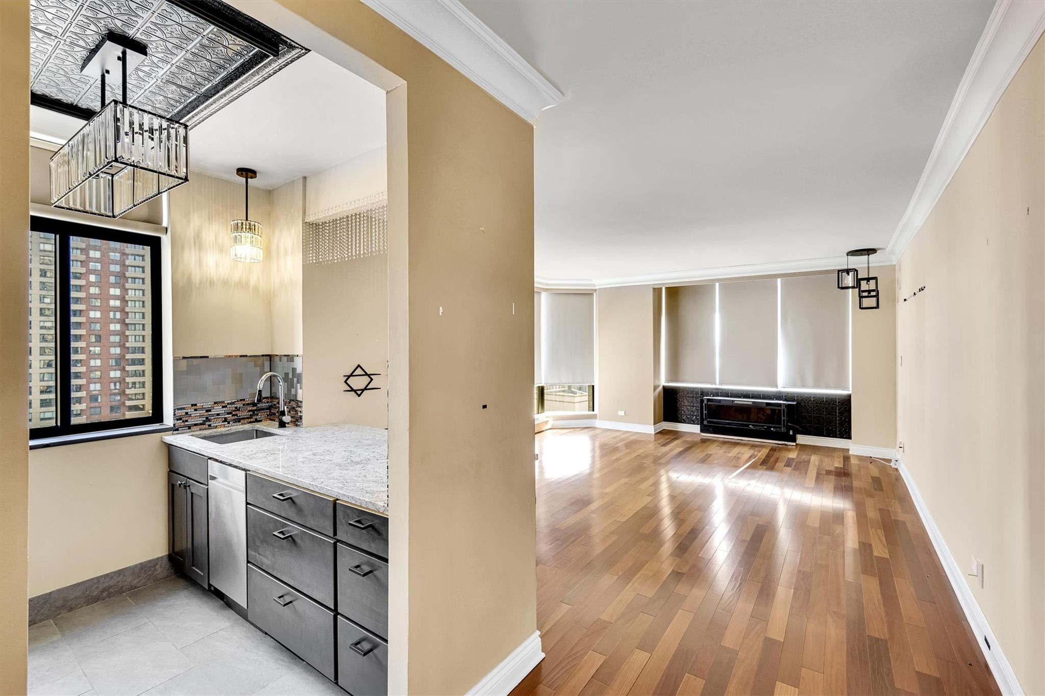 380 Rector Place, Unit 15E Manhattan, NY 10280 - Photo 6 of 31 Kitchen with baseboards, light wood finished floors, ornamental molding, decorative backsplash, and a sink