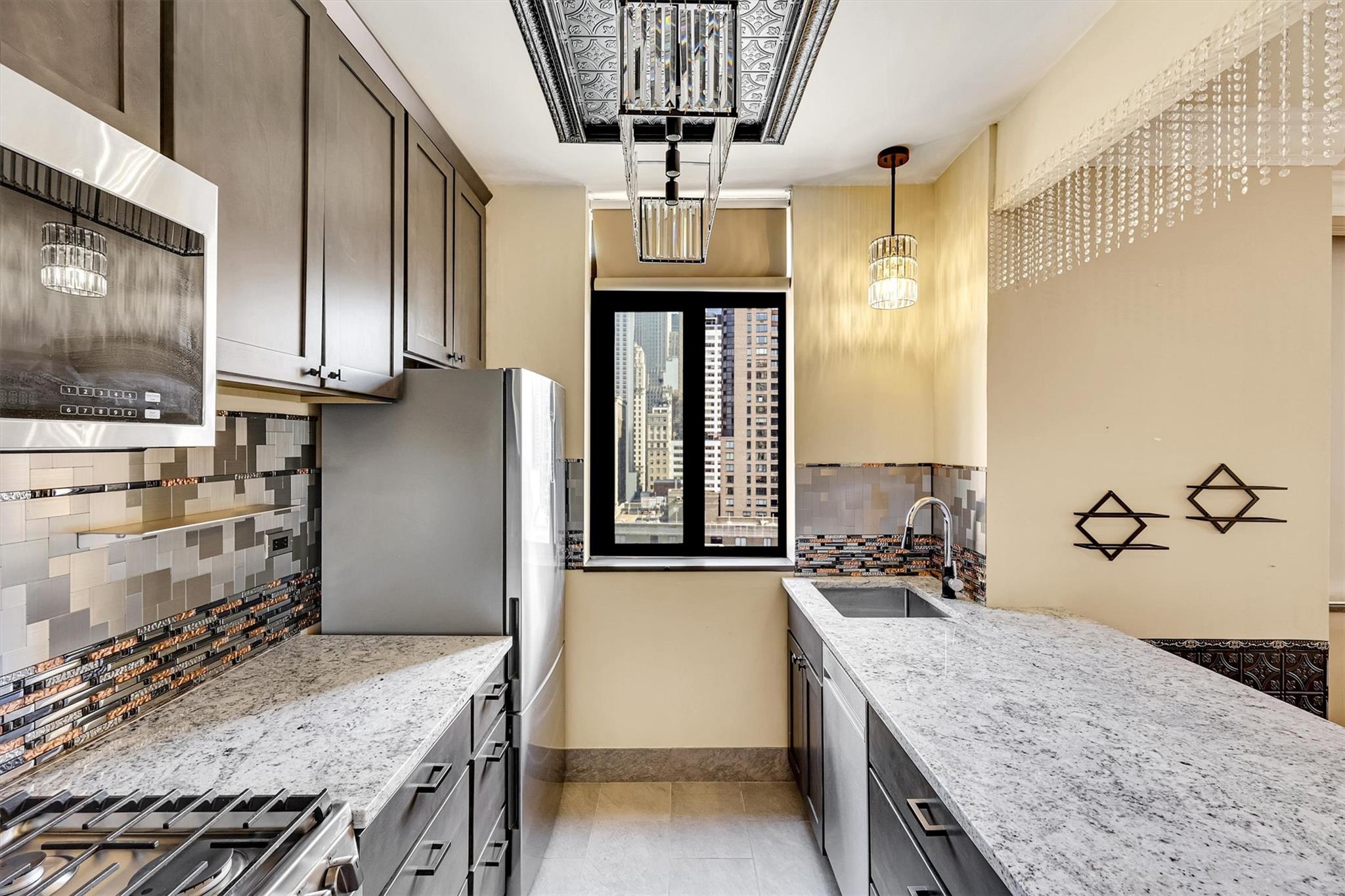 380 Rector Place, Unit 15E Manhattan, NY 10280 - Photo 8 of 31 Kitchen with backsplash, baseboards, light stone counters, appliances with stainless steel finishes, and a sink