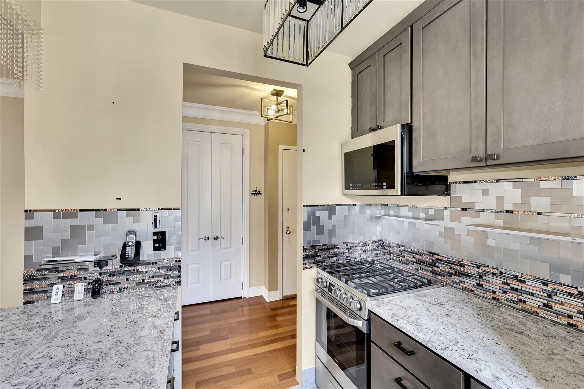380 Rector Place, Unit 15E Manhattan, NY 10280 - Photo 10 of 31 Kitchen featuring light stone counters, wood finished floors, appliances with stainless steel finishes, and ornamental molding