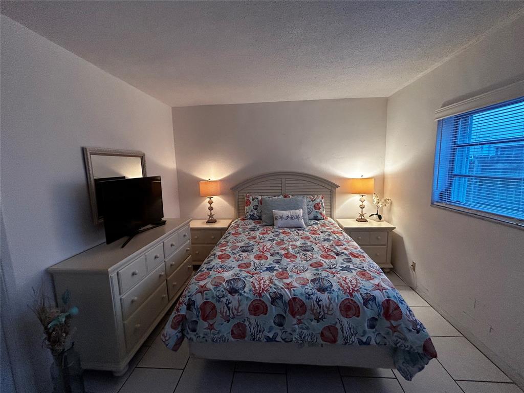 4630 Poinciana Street, Unit 1C Lauderdale-by-the-Sea, FL 33308 - Photo 5 of 7 a bedroom with a bed and a flat screen tv
