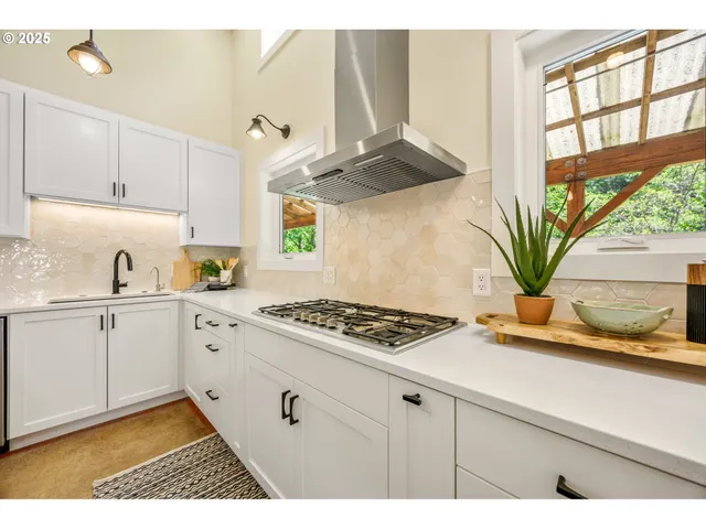 a kitchen with stainless steel appliances a white stove top oven cabinets a chimney and a window