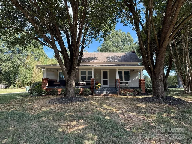 a view of a house with large trees and wooden fence