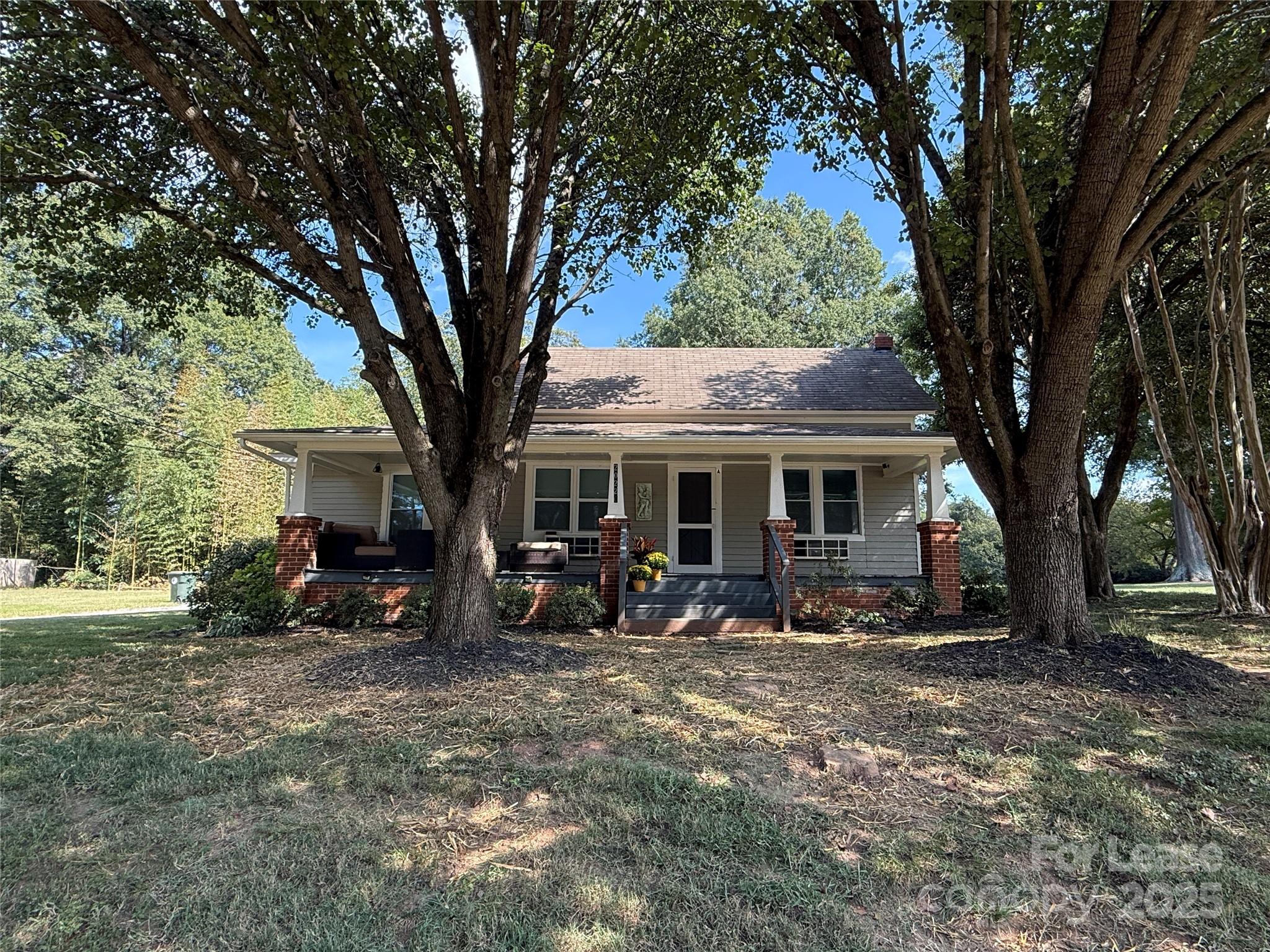 a view of a house with large trees and wooden fence