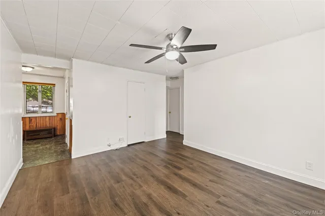 an empty room with ceiling fan and windows
