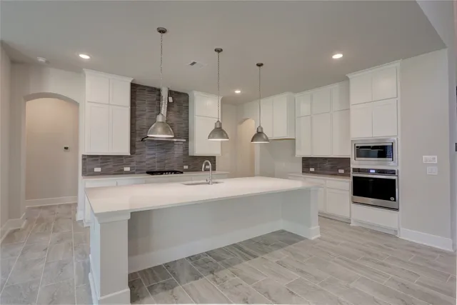 a large kitchen with stainless steel appliances a large counter top a stove and a refrigerator