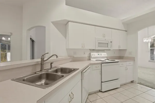 a kitchen with sink a stove and white cabinets