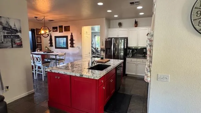a living room with stainless steel appliances kitchen island granite countertop a table chairs and a refrigerator