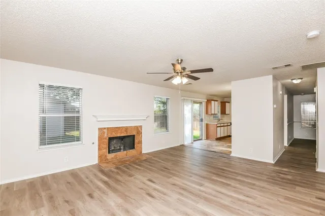 a view of a livingroom with wooden floor a ceiling fan and windows