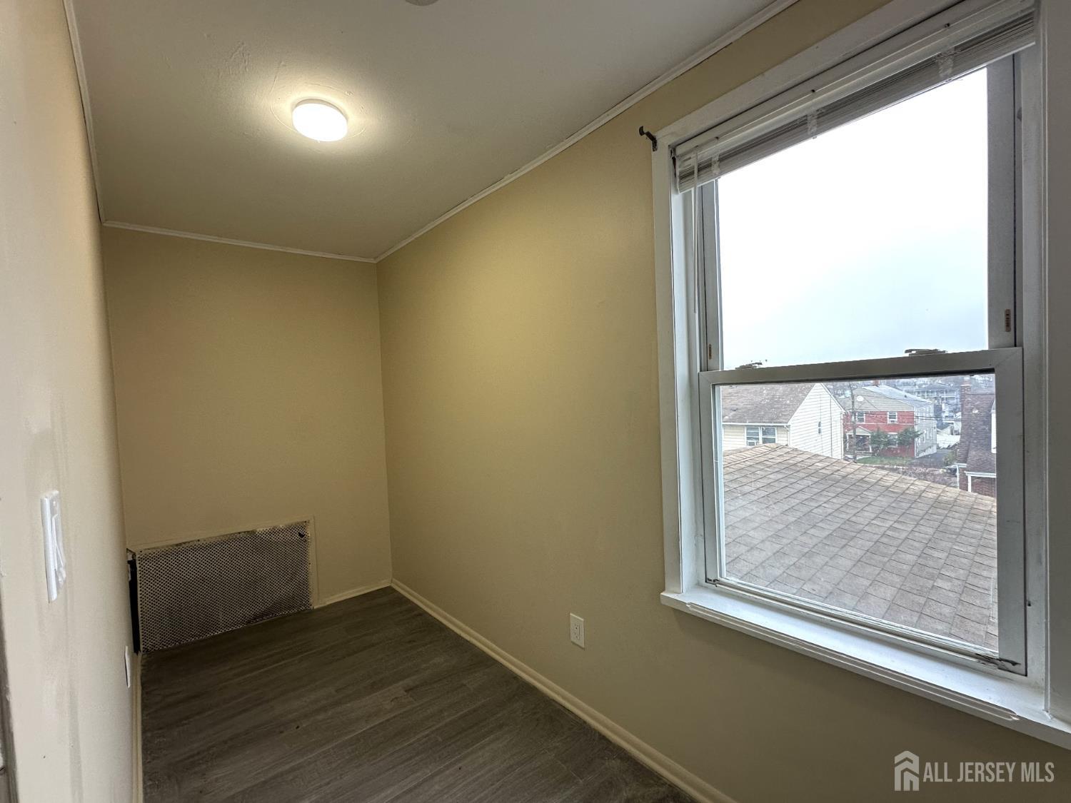 618 Carlock Avenue Perth Amboy, NJ 08861 - Photo 4 of 9 an empty room with wooden floor and windows