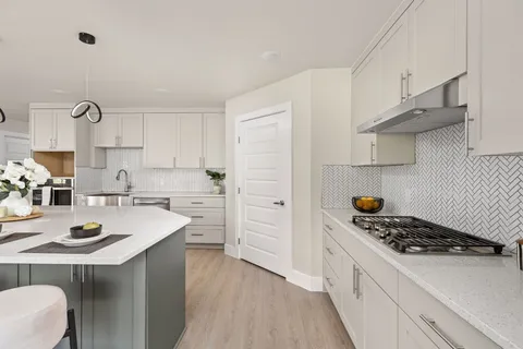 a kitchen with kitchen island a sink a stove and cabinets