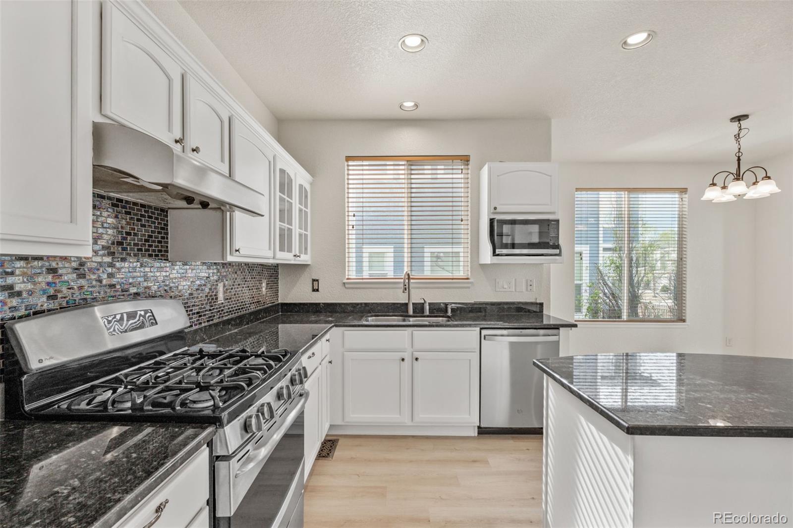 10665 Evondale Street Highlands Ranch, CO 80126 - Photo 12 of 45 a large kitchen with stainless steel appliances granite countertop a stove a sink dishwasher and cabinets with wooden floor