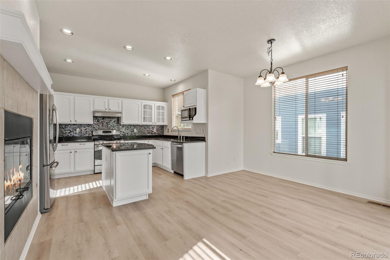 10665 Evondale Street Highlands Ranch, CO 80126 - Photo 9 of 45 a kitchen with white cabinets and stainless steel appliances