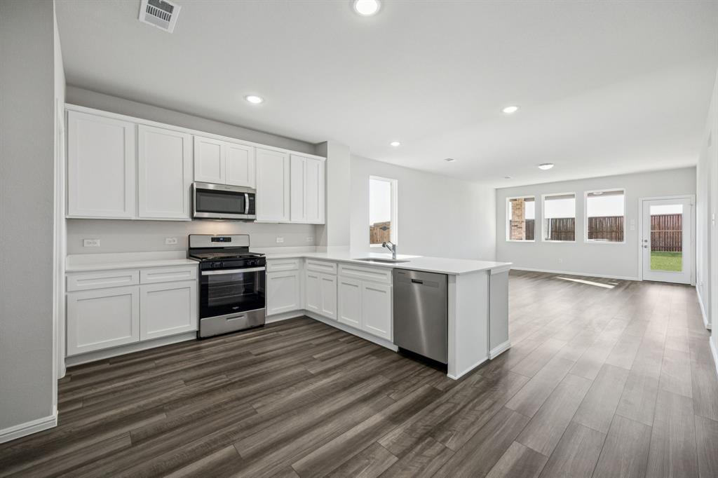 425 Magellan Road Seagoville, TX 75159 - Photo 5 of 36 a kitchen with wooden floors and white appliances