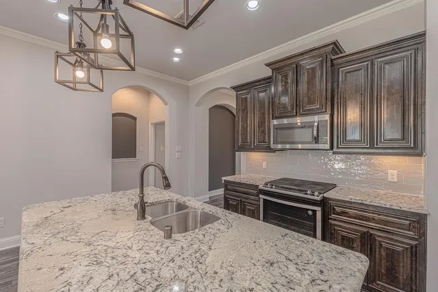a kitchen with stainless steel appliances granite countertop a sink stove and cabinets