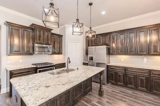 a kitchen with stainless steel appliances granite countertop hardwood floor sink stove and refrigerator