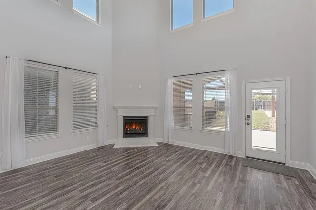 an empty room with wooden floor fireplace and windows
