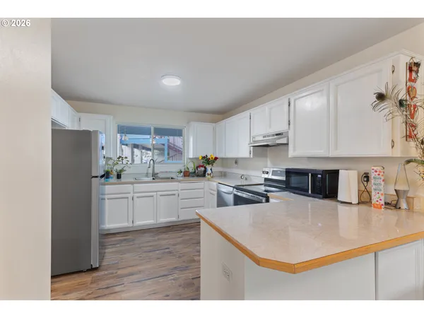 a kitchen with stainless steel appliances a sink a stove a refrigerator cabinets and a window