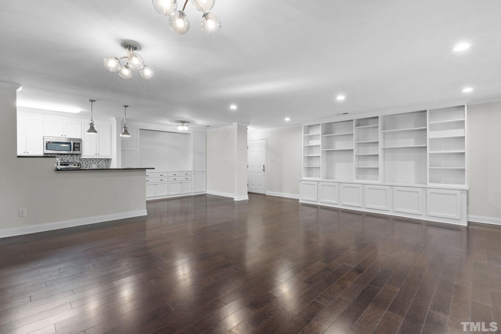 4505 Edwards Mill Road, Unit G Raleigh, NC 27612 - Photo 12 of 31 an empty room with wooden floor and kitchen view