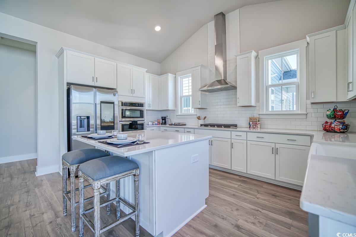 3810 Richardson Street Loris, SC 29569 - Photo 12 of 40 Kitchen featuring white cabinets, lofted ceiling, a breakfast bar, a center island, and decorative backsplash