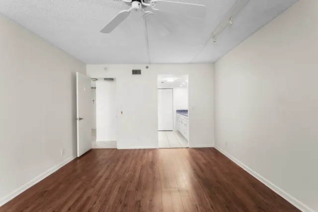 a view of empty room with wooden floor and ceiling fan