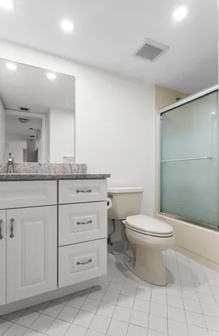 a bathroom with a granite countertop toilet a sink a mirror and vanity
