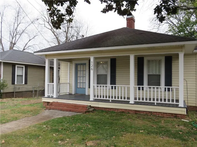 a view of a house with a yard and a large tree