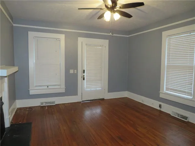 a view of an empty room with wooden floor and a window