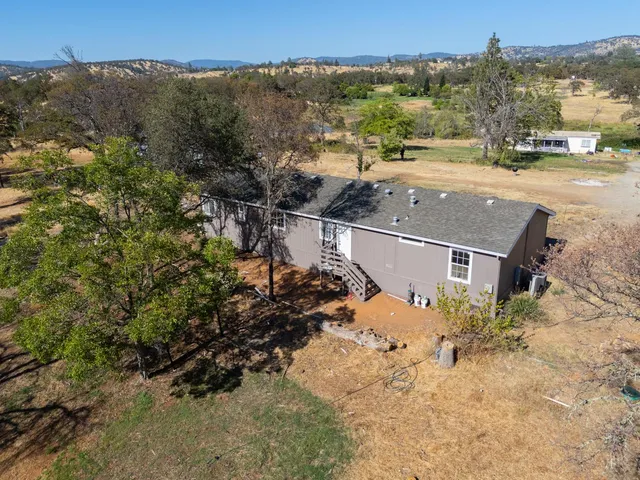 an aerial view of a house with a yard and mountain view in back